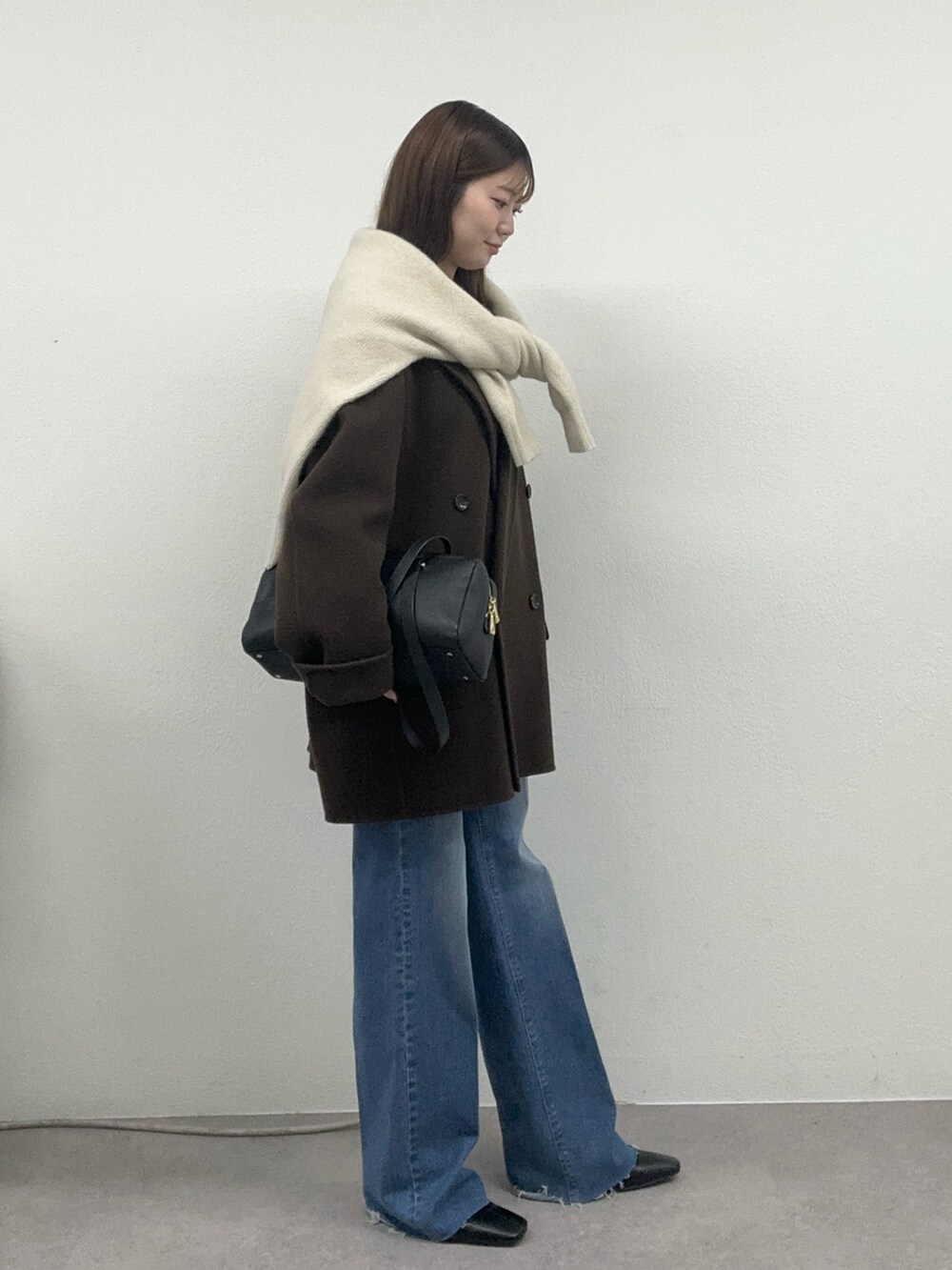 ブラウン系のその他アウター、ブルー系のデニムパンツ、ベージュ系のニット/セーターを着用したレディースの秋コーディネートの2枚目の写真