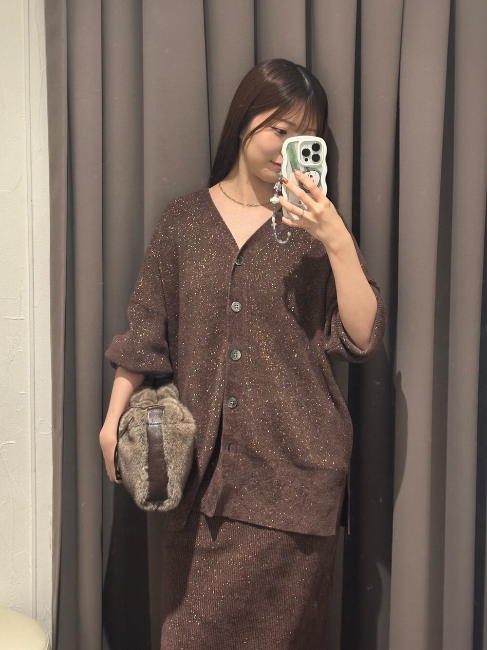 ブラウン系のニット/セーター、ブラウン系のスカート、ブラウン系のハンドバッグを着用したレディースの秋コーディネートの2枚目の写真