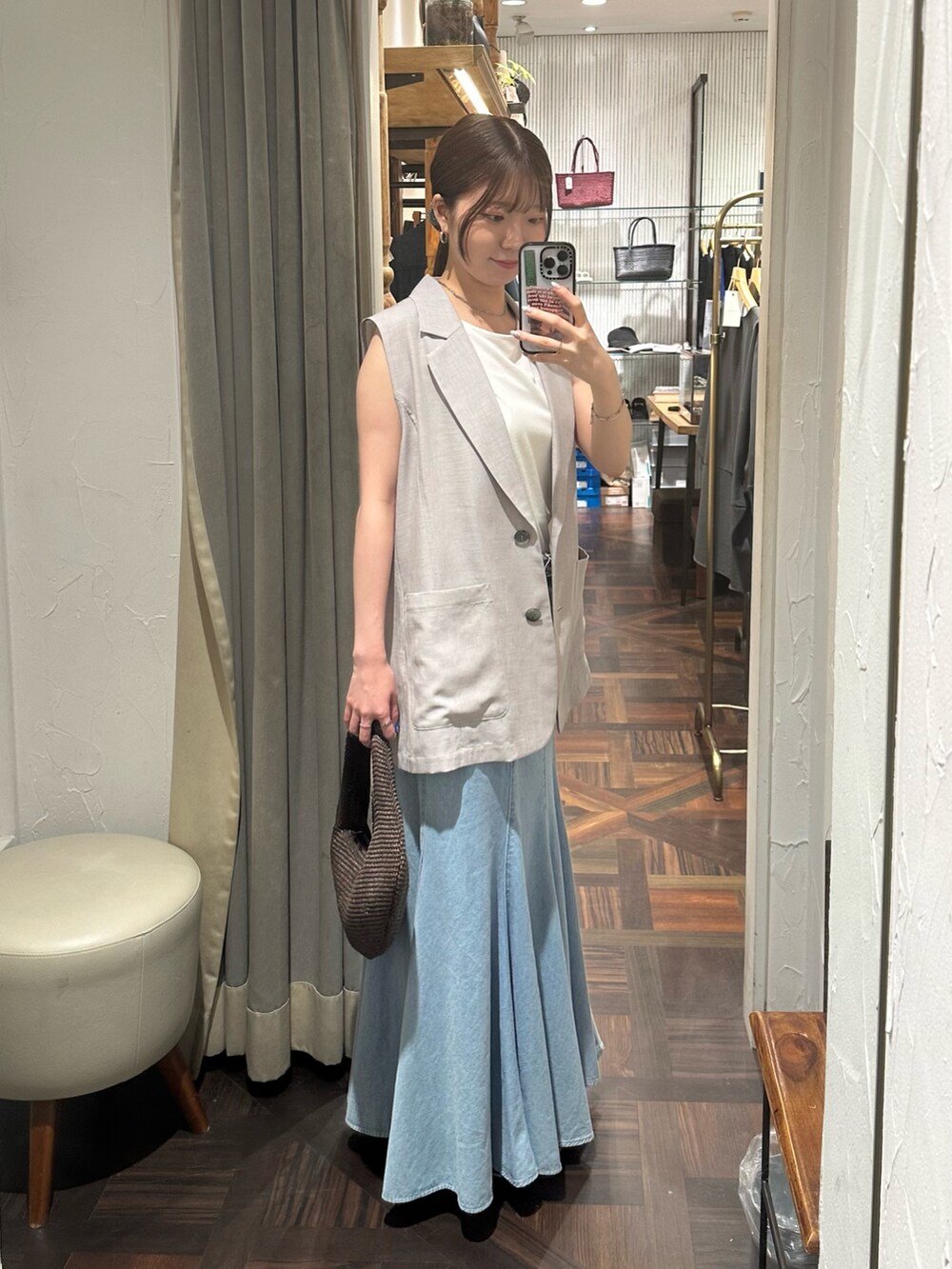 ブルー系のスカート、グレー系のベスト、ブラック系のサンダルを着用したレディースの夏コーディネートの4枚目の写真