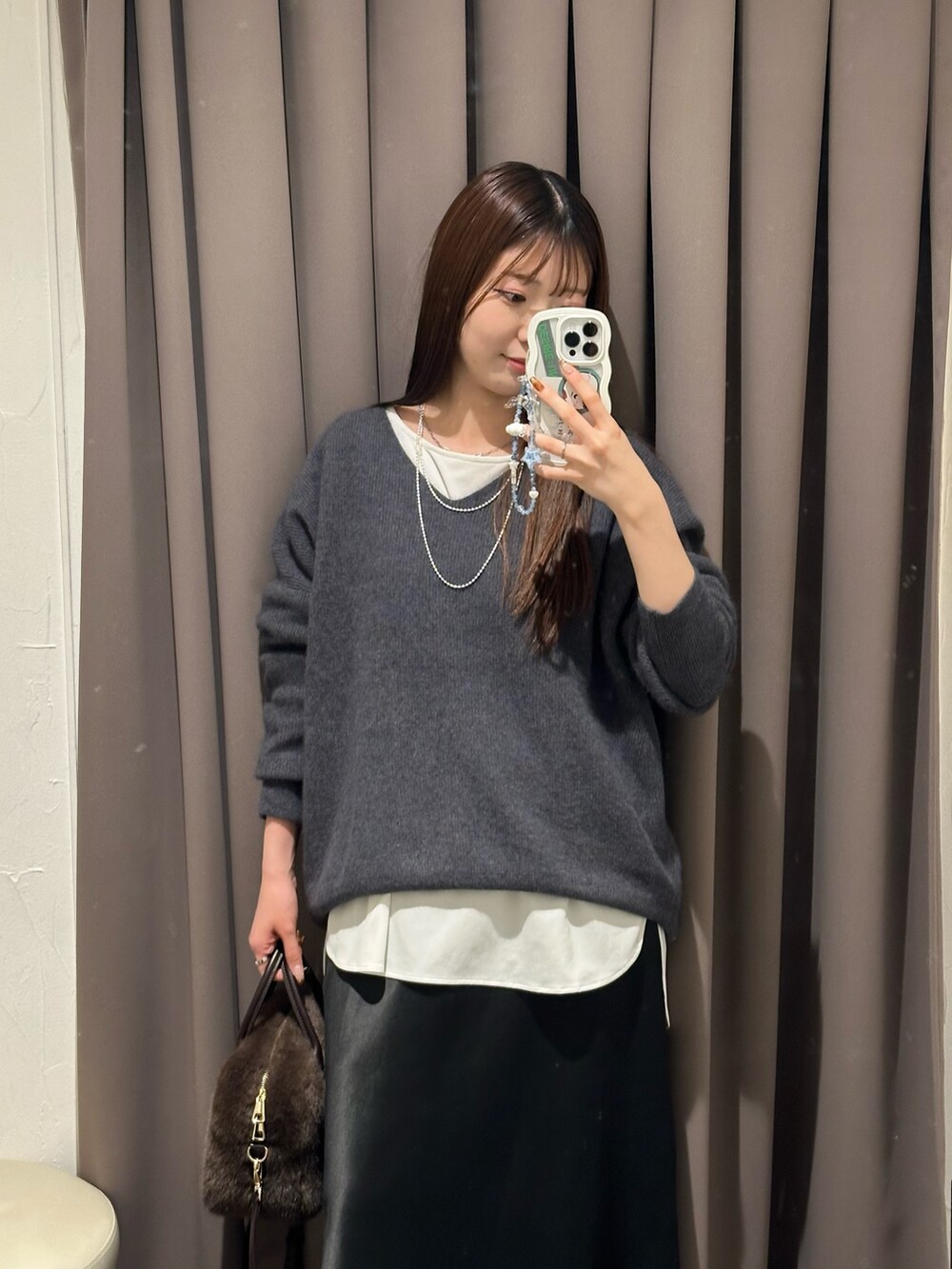 グレー系のニット/セーター、ホワイト系のTシャツ/カットソー、ブラック系のスカートを着用したレディースの冬コーディネートの2枚目の写真