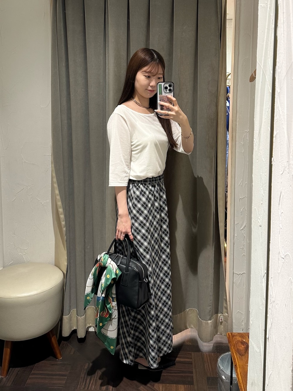ブラック系のスカート、ホワイト系のTシャツ/カットソー、ブラック系のボストンバッグを着用したレディースの夏コーディネートの3枚目の写真