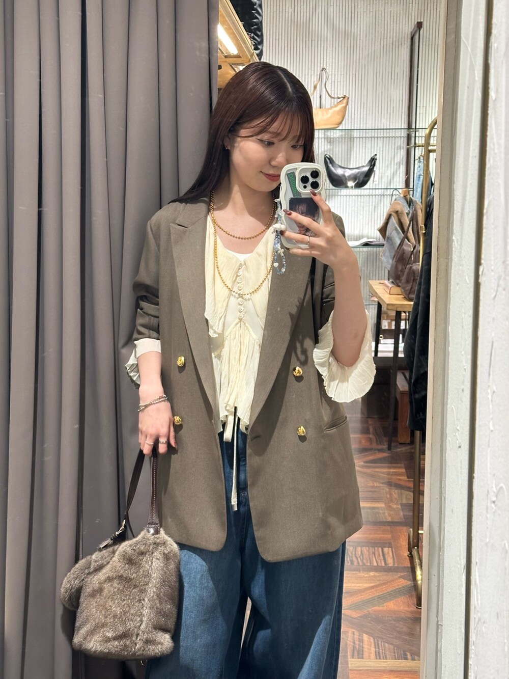 ブラウン系のテーラードジャケット、ホワイト系のシャツ/ブラウス、ブルー系のデニムパンツを着用したレディースの秋コーディネートの2枚目の写真