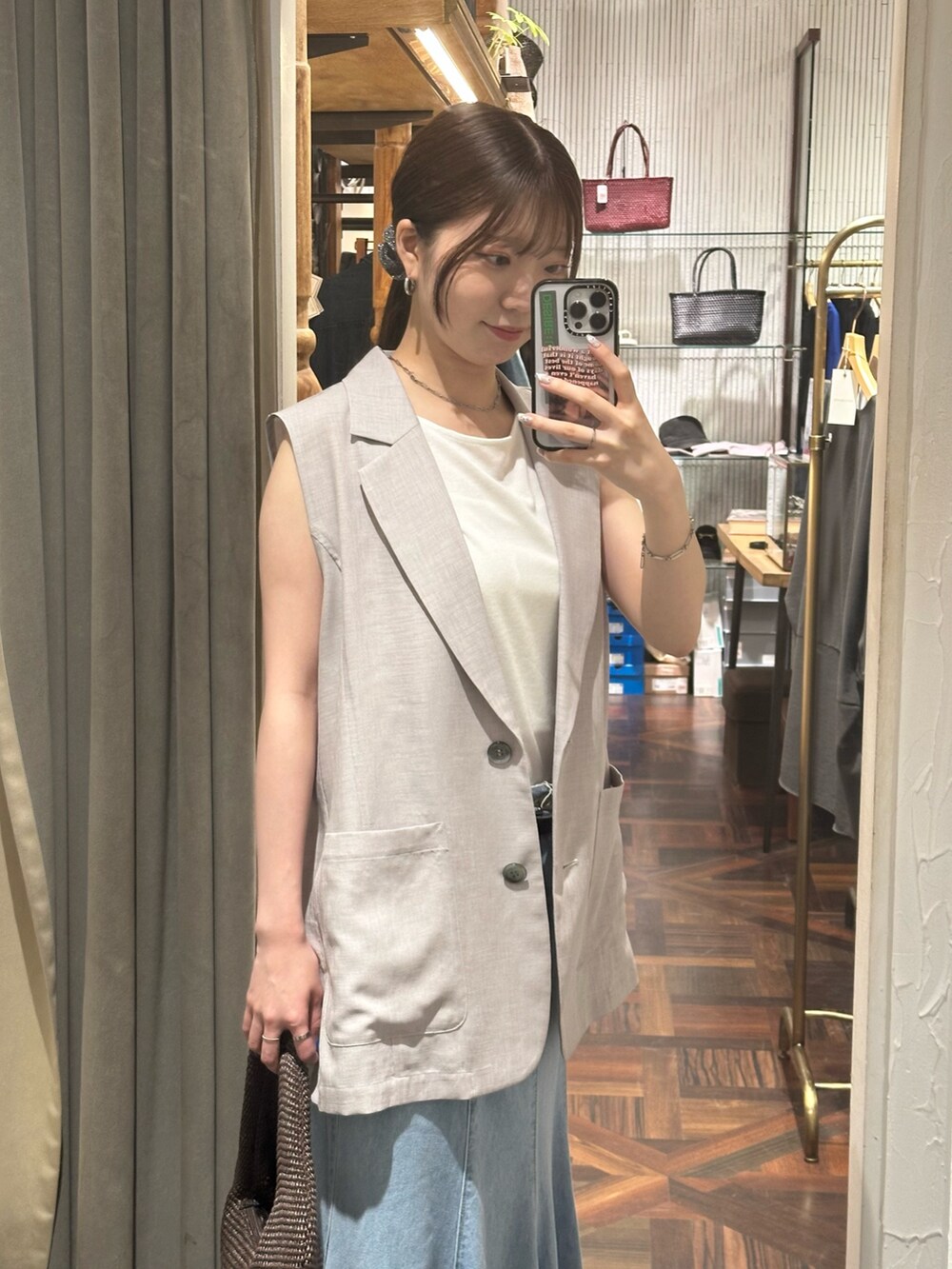 ブルー系のスカート、グレー系のベスト、ブラック系のサンダルを着用したレディースの夏コーディネートの3枚目の写真