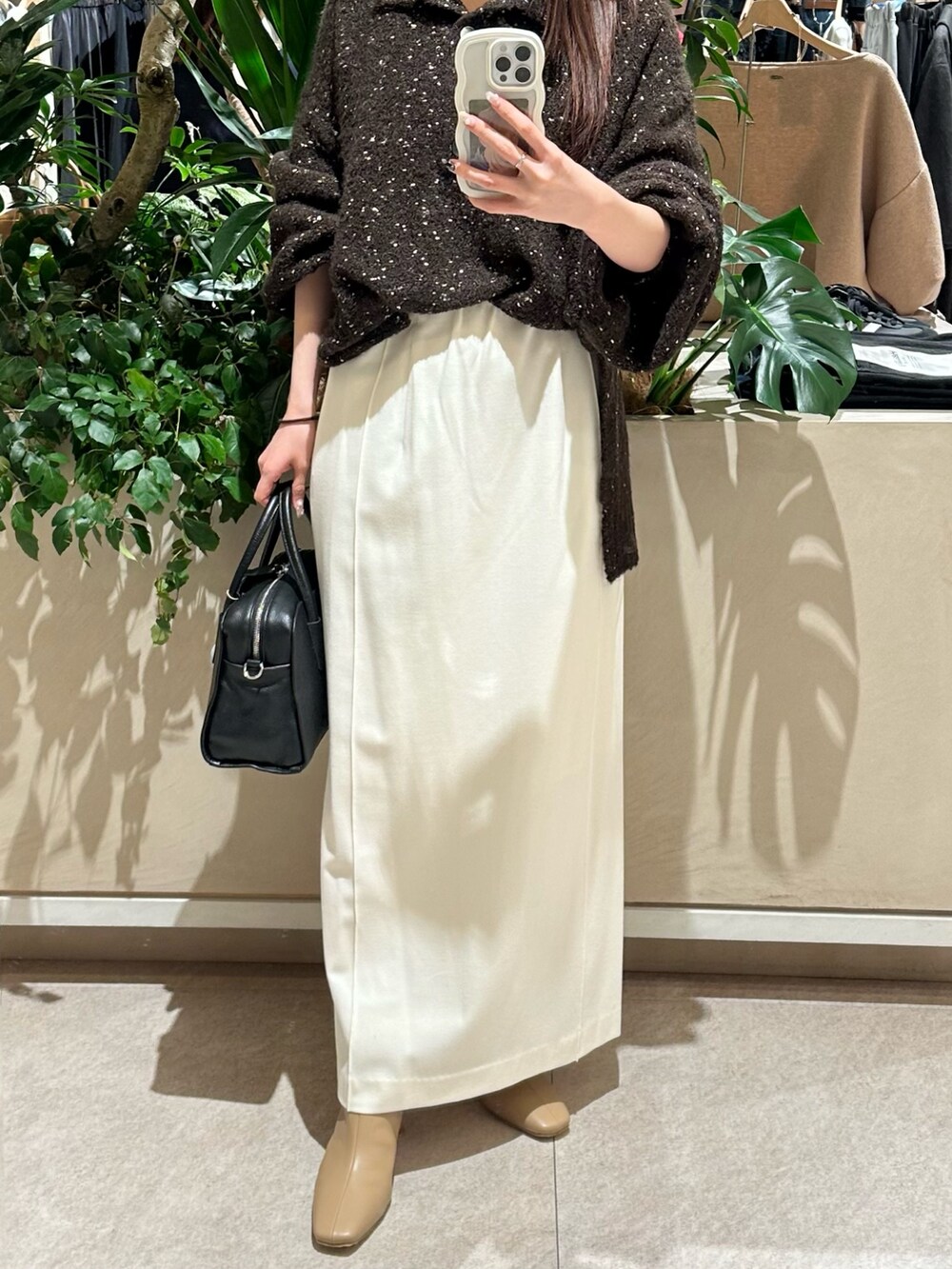 ホワイト系のスカート、ベージュ系のブーツ、ブラック系のボストンバッグを着用したレディースの冬コーディネートの2枚目の写真