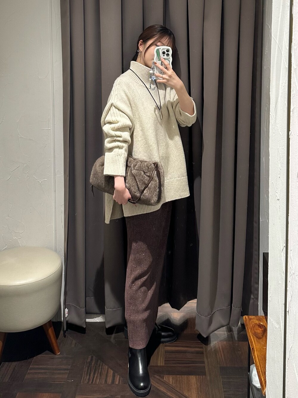 ブラウン系のスカート、ブラック系のブーツ、ブラウン系のハンドバッグを着用したレディースの秋コーディネートの4枚目の写真