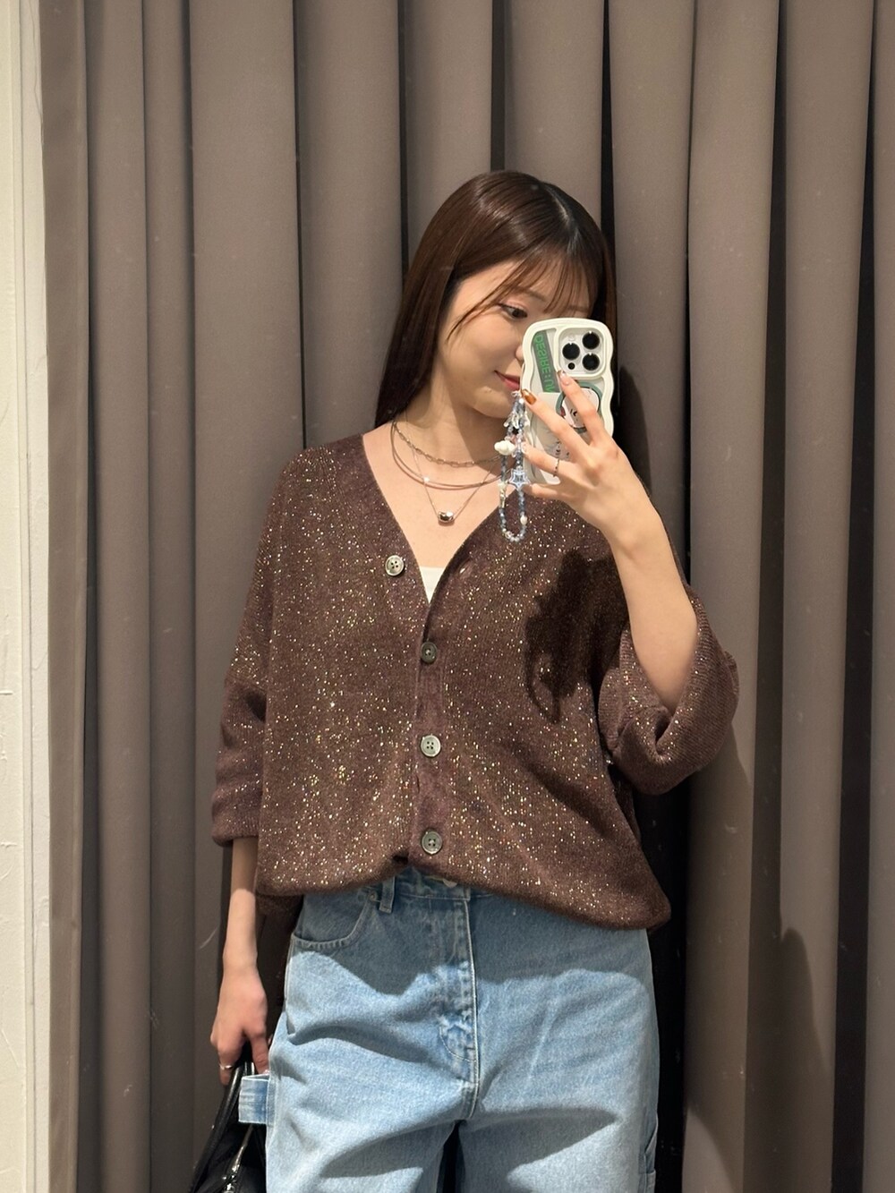 ブラウン系のニット/セーター、ブラック系のブーツ、ブルー系のデニムパンツを着用したレディースの秋コーディネートの2枚目の写真