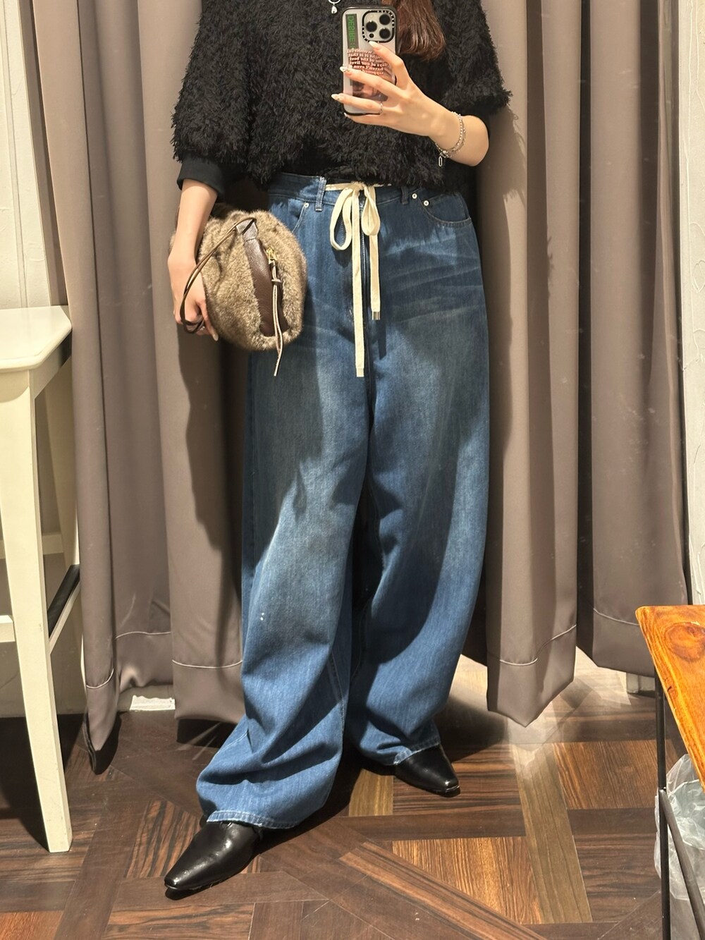 ブルー系のデニムパンツ、ブラック系のシャツ/ブラウス、ブラウン系のハンドバッグを着用したレディースの秋コーディネートの2枚目の写真