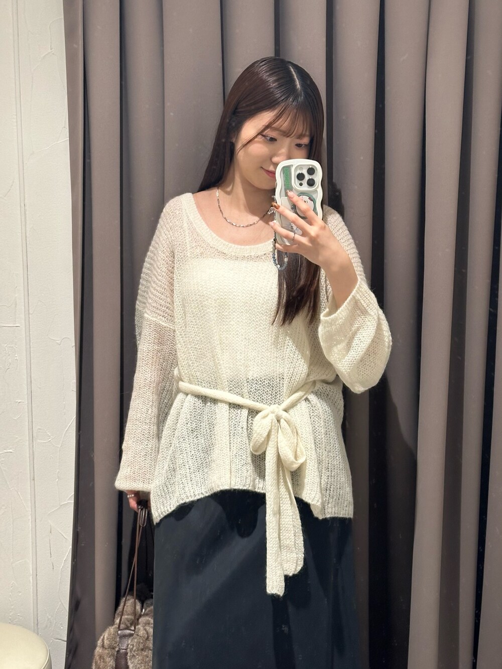 ホワイト系のニット/セーター、ブラック系のブーツ、ブラウン系のハンドバッグを着用したレディースの秋コーディネートの2枚目の写真