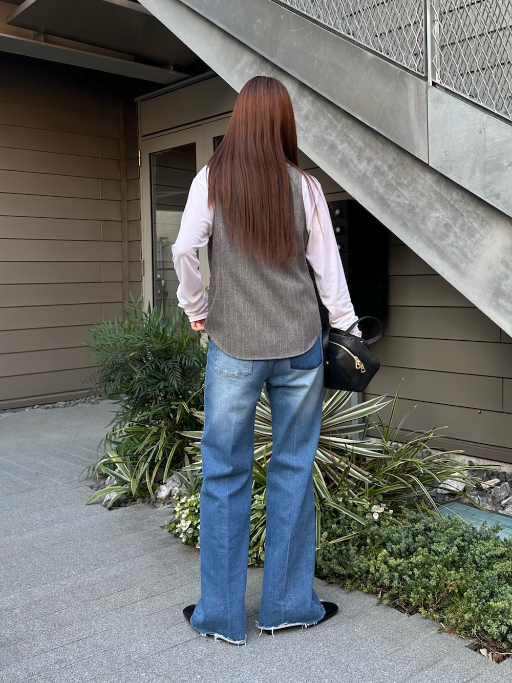 ブルー系のデニムパンツ、ホワイト系のTシャツ/カットソー、グレー系のベストを着用したレディースの秋コーディネートの2枚目の写真