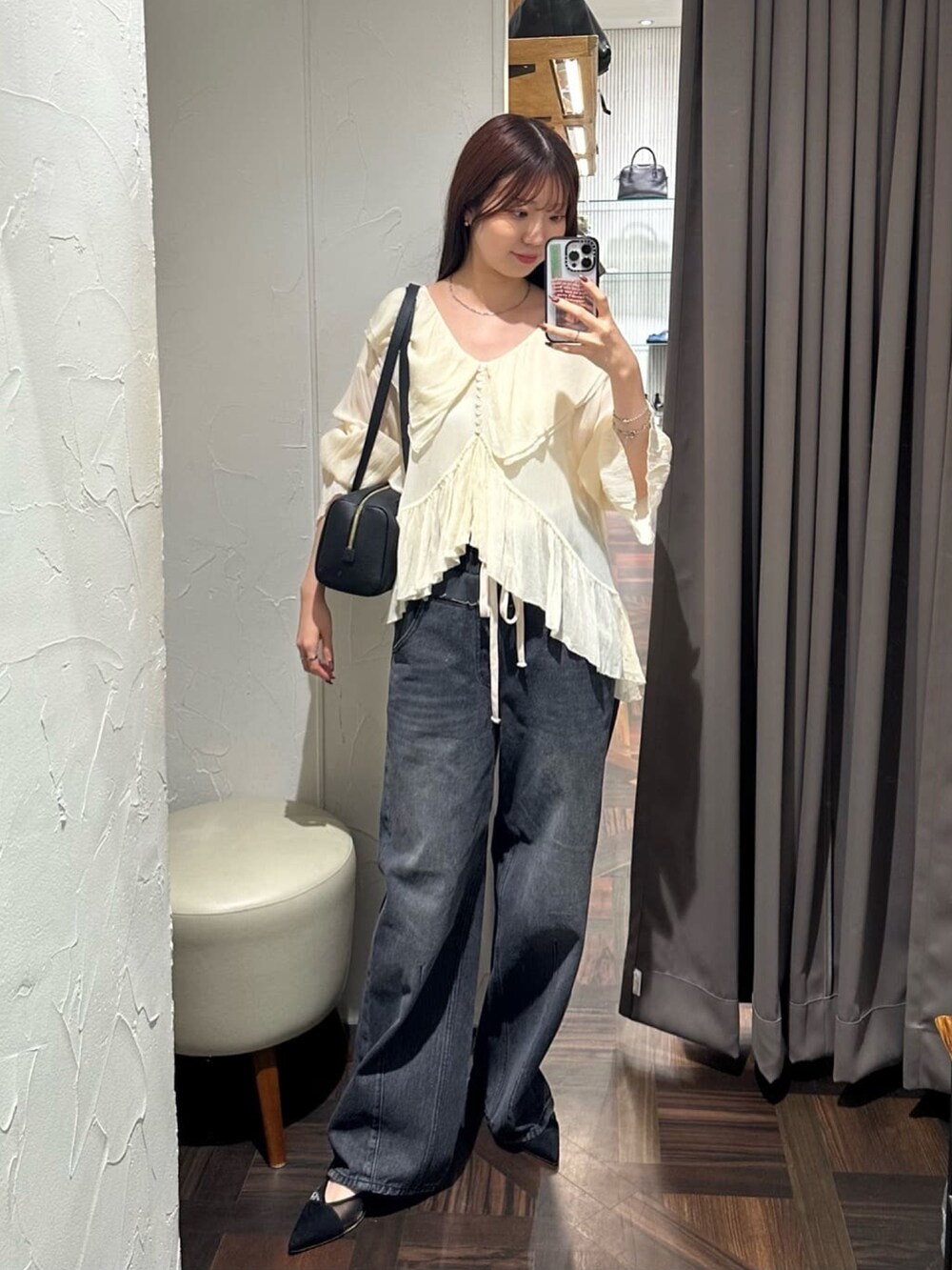 グレー系のテーラードジャケット、ブラック系のデニムパンツ、ブラック系のパンプスを着用したレディースの秋コーディネートの4枚目の写真