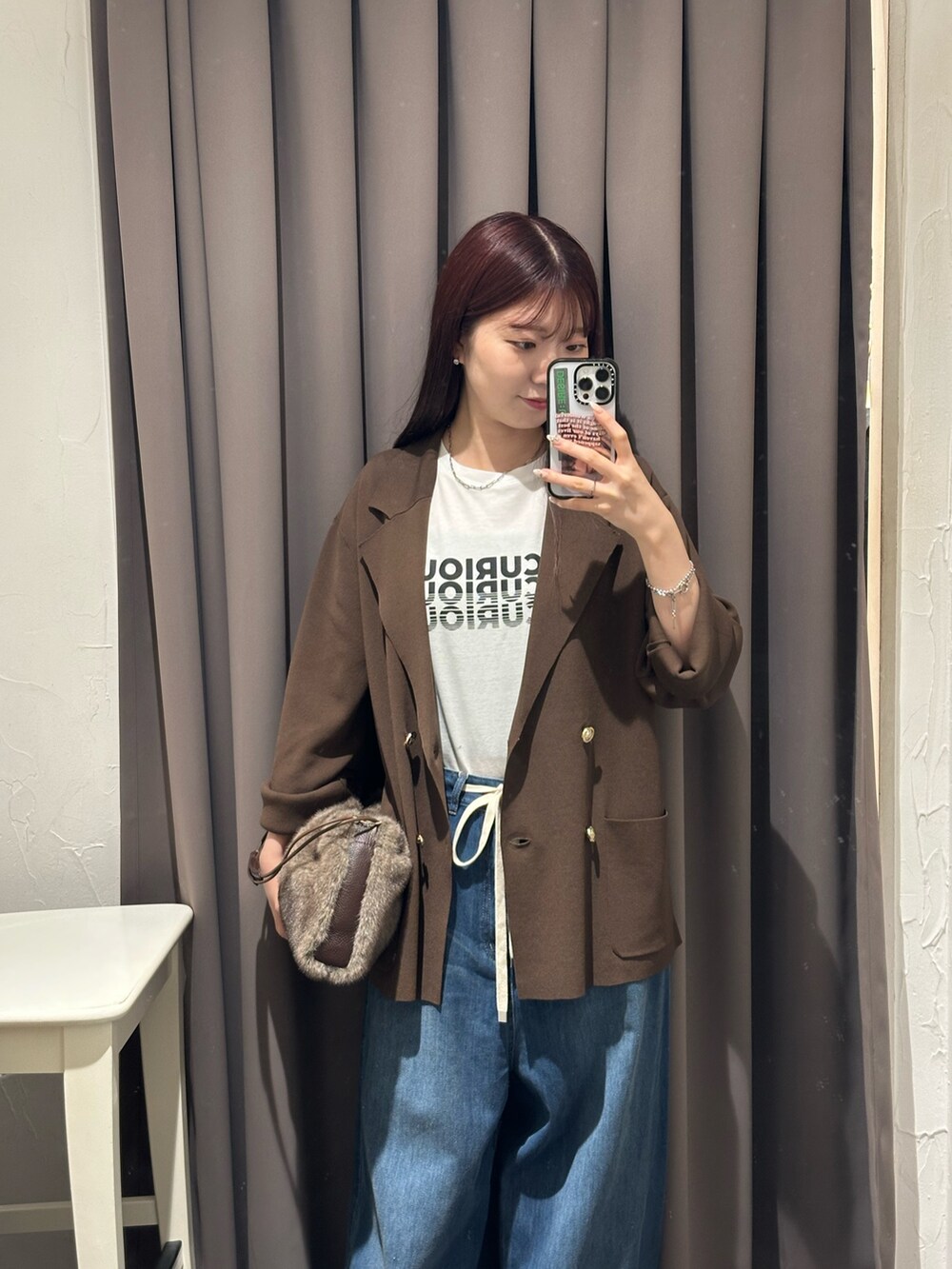 ブルー系のデニムパンツ、ブラウン系のテーラードジャケット、ブラウン系のハンドバッグを着用したレディースの夏コーディネートの2枚目の写真