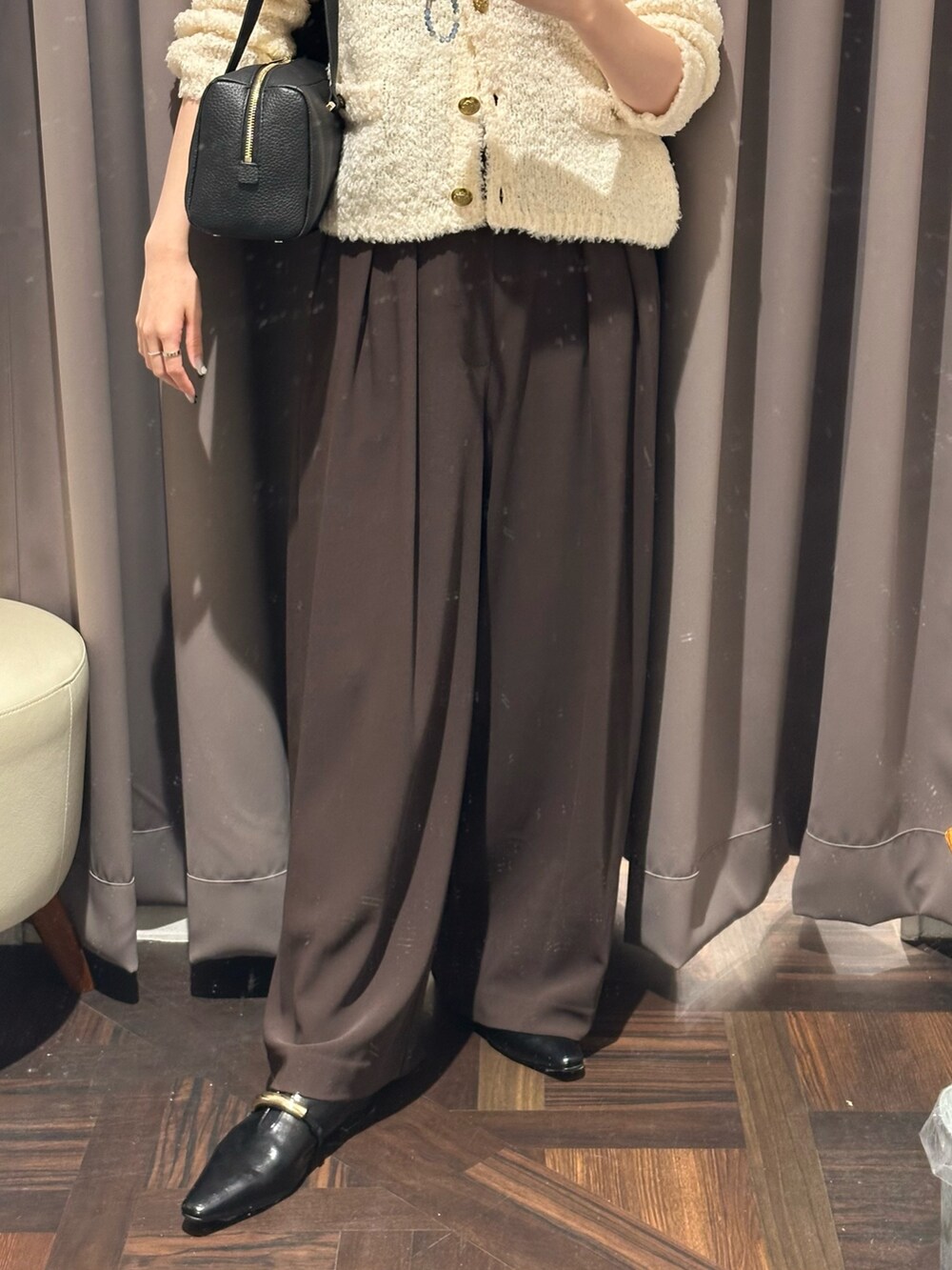 ブラウン系のスラックス、ホワイト系のカーディガン/ボレロ、ブラック系のショルダーバッグを着用したレディースの秋コーディネートの3枚目の写真