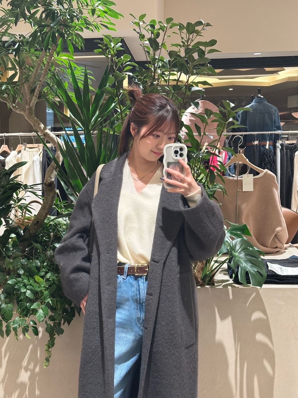 ホワイト系のニット/セーター、ブルー系のデニムパンツ、ブラウン系のチェスターコートを着用したレディースの冬コーディネートの2枚目の写真