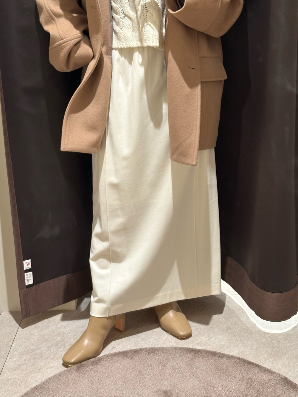 イエロー系のその他アウター、ホワイト系のスカート、ベージュ系のブーツを着用したレディースの冬コーディネートの3枚目の写真