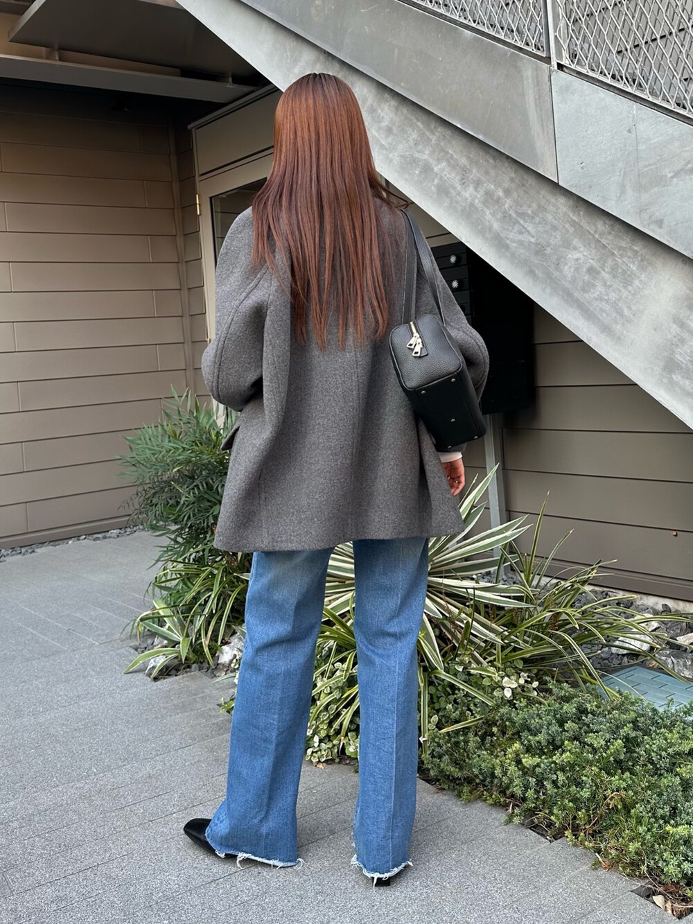 グレー系のピーコート、ブルー系のデニムパンツ、ブラウン系のブーツを着用したレディースの秋コーディネートの2枚目の写真