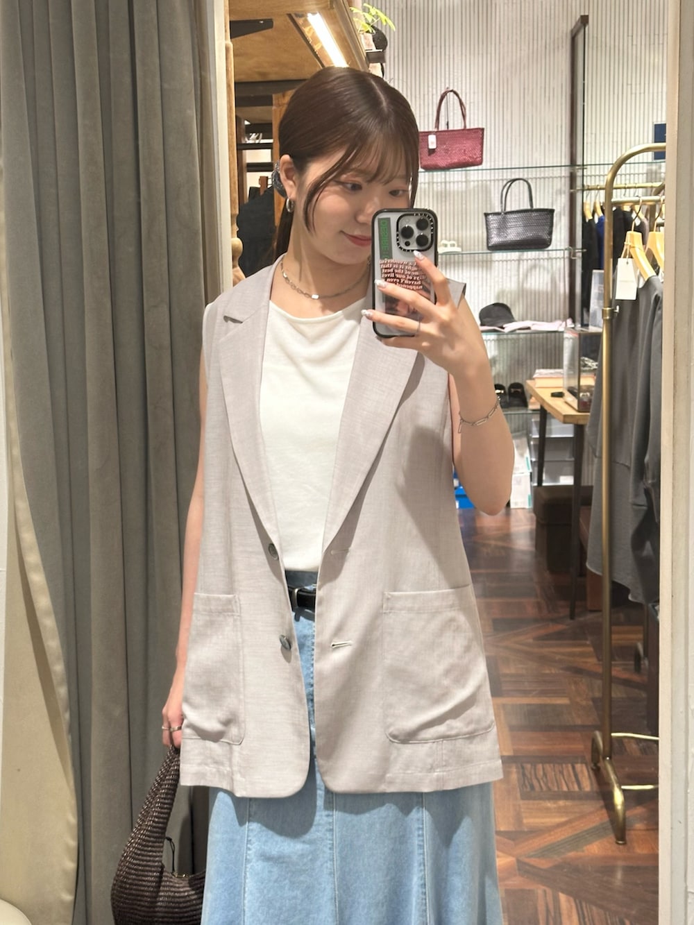 ブルー系のスカート、グレー系のベスト、ブラック系のサンダルを着用したレディースの夏コーディネートの2枚目の写真