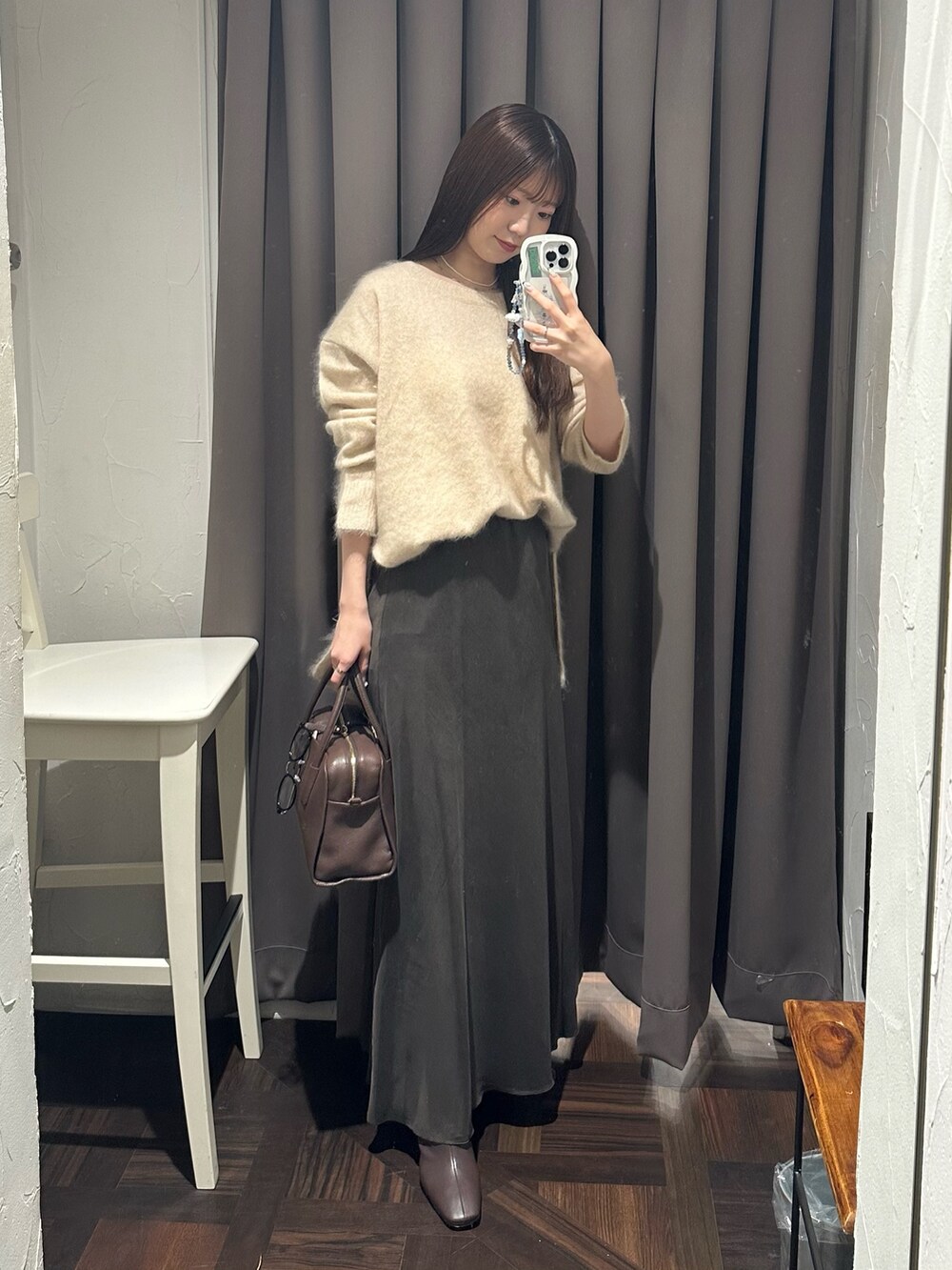 ブラウン系のスカート、ベージュ系のニット/セーター、ブラウン系のブーツを着用したレディースの秋コーディネートの2枚目の写真