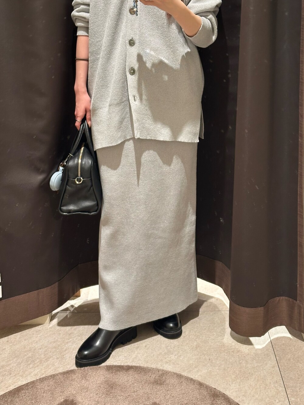 グレー系のニット/セーター、グレー系のスカート、ブラック系のボストンバッグを着用したレディースの冬コーディネートの3枚目の写真