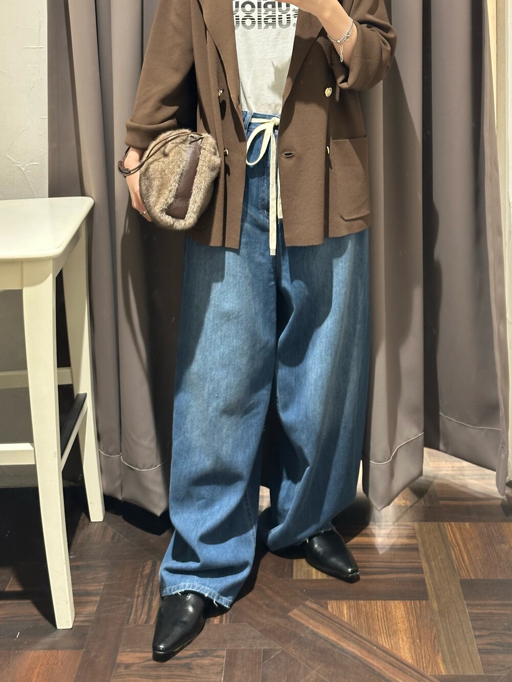 ブルー系のデニムパンツ、ブラウン系のテーラードジャケット、ブラウン系のハンドバッグを着用したレディースの夏コーディネートの3枚目の写真