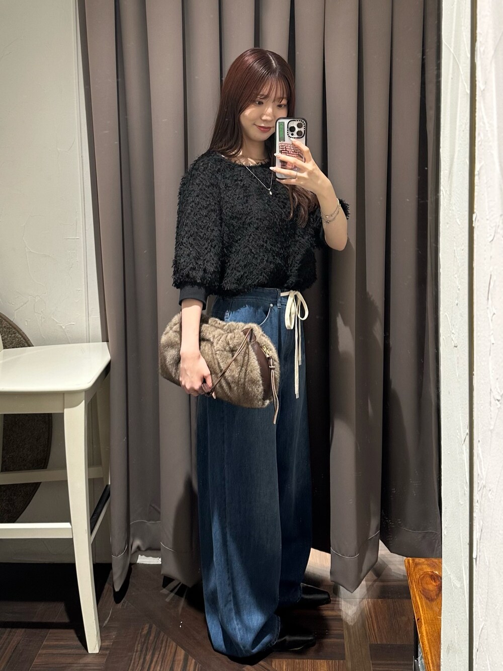 ブルー系のデニムパンツ、ブラック系のシャツ/ブラウス、ブラウン系のハンドバッグを着用したレディースの秋コーディネートの3枚目の写真