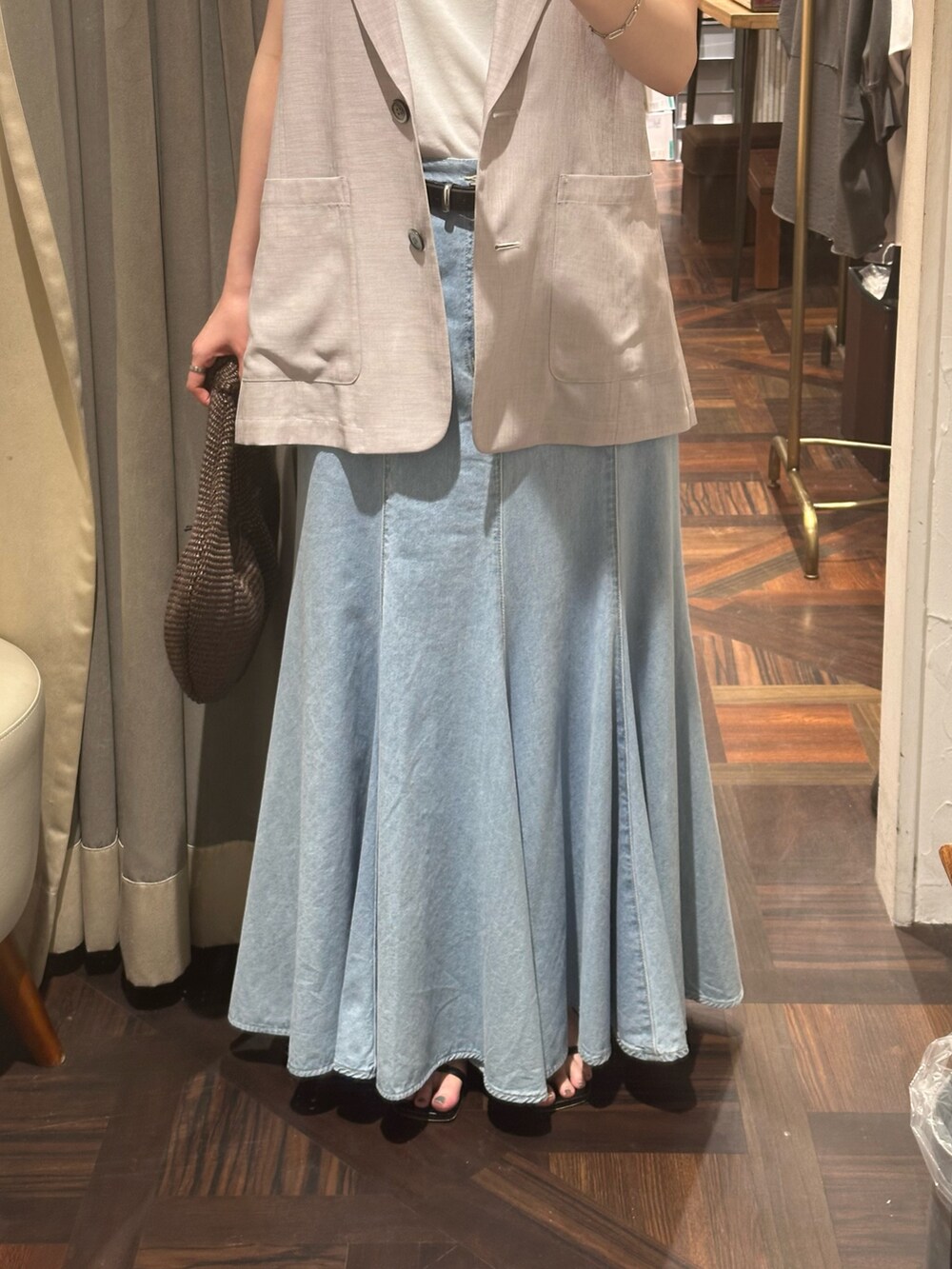 ブルー系のスカート、グレー系のベスト、ブラック系のサンダルを着用したレディースの夏コーディネートの5枚目の写真