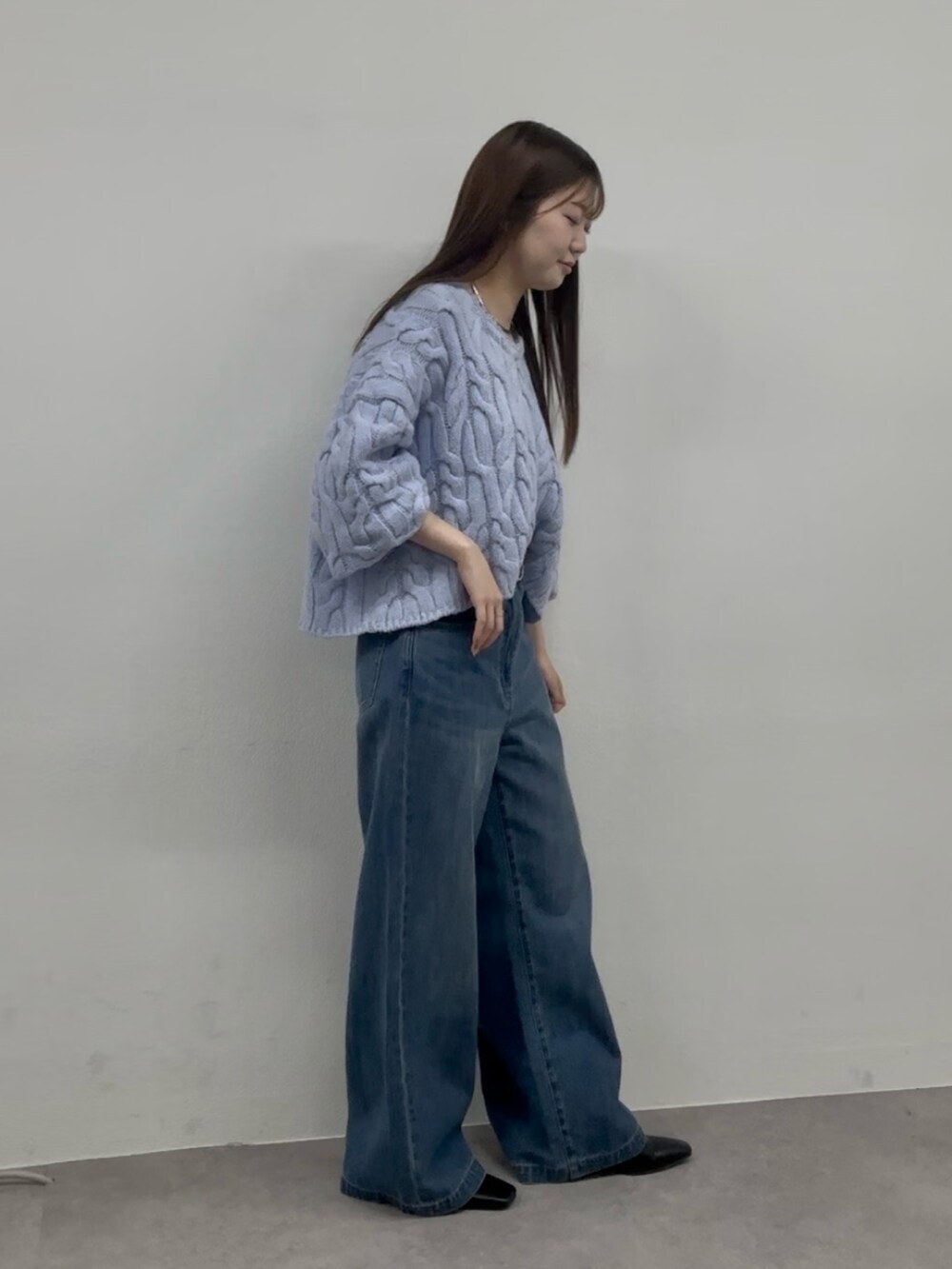 ブルー系のニット/セーター、ブルー系のデニムパンツ、ブラウン系のブーツを着用したレディースの秋コーディネートの2枚目の写真