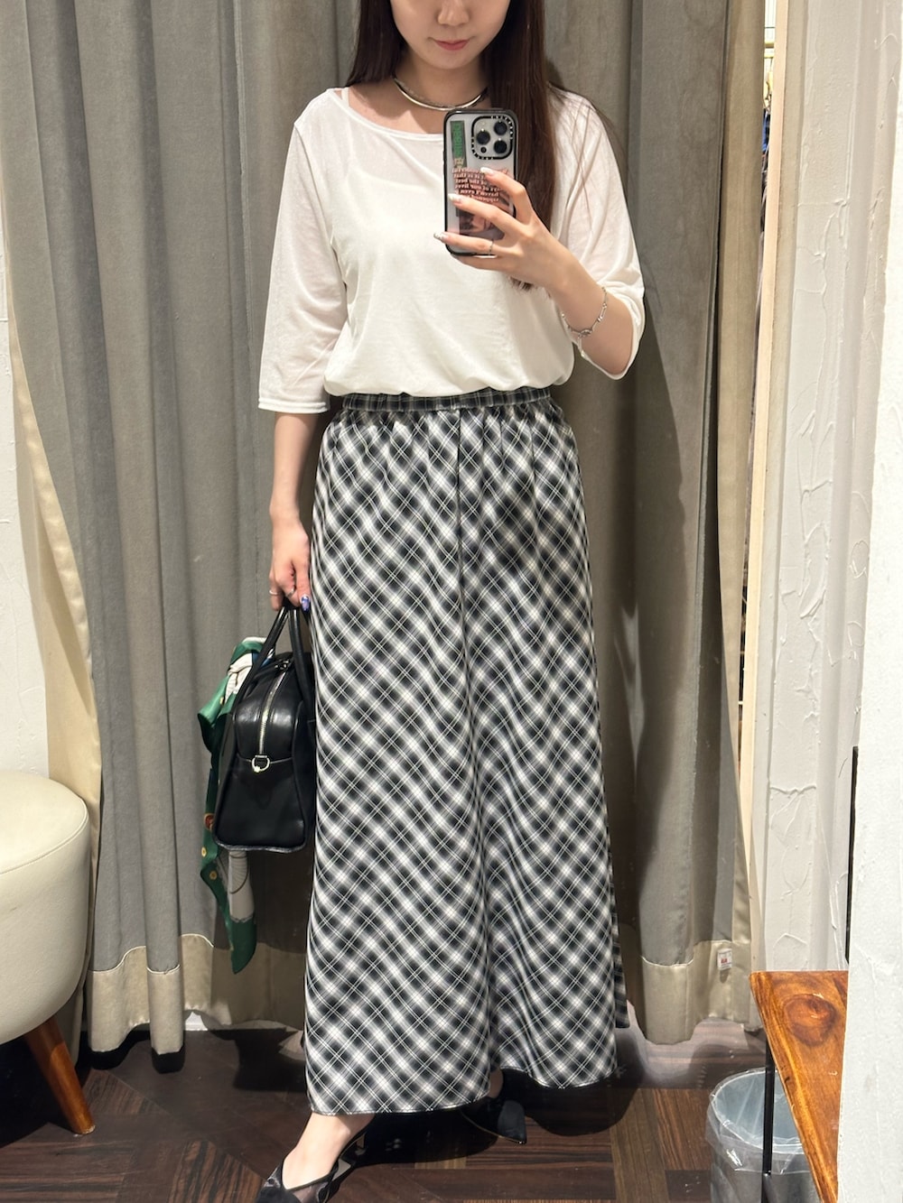ブラック系のスカート、ホワイト系のTシャツ/カットソー、ブラック系のボストンバッグを着用したレディースの夏コーディネートの2枚目の写真