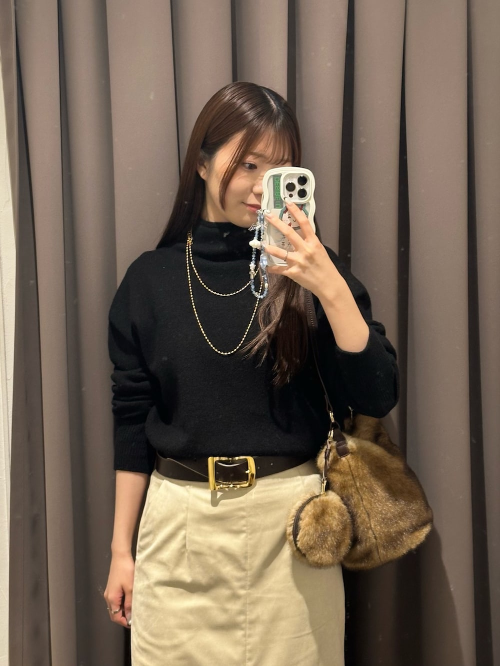 ブラック系のニット/セーター、ベージュ系のスカート、イエロー系のハンドバッグを着用したレディースの秋コーディネートの3枚目の写真