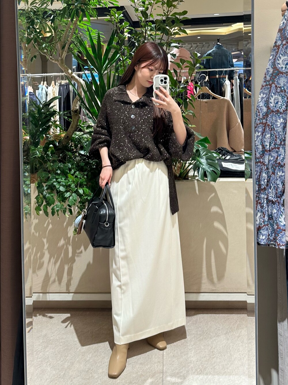 ブラウン系のニット/セーター、ホワイト系のスカート、ベージュ系のブーツを着用したレディースの冬コーディネートの3枚目の写真