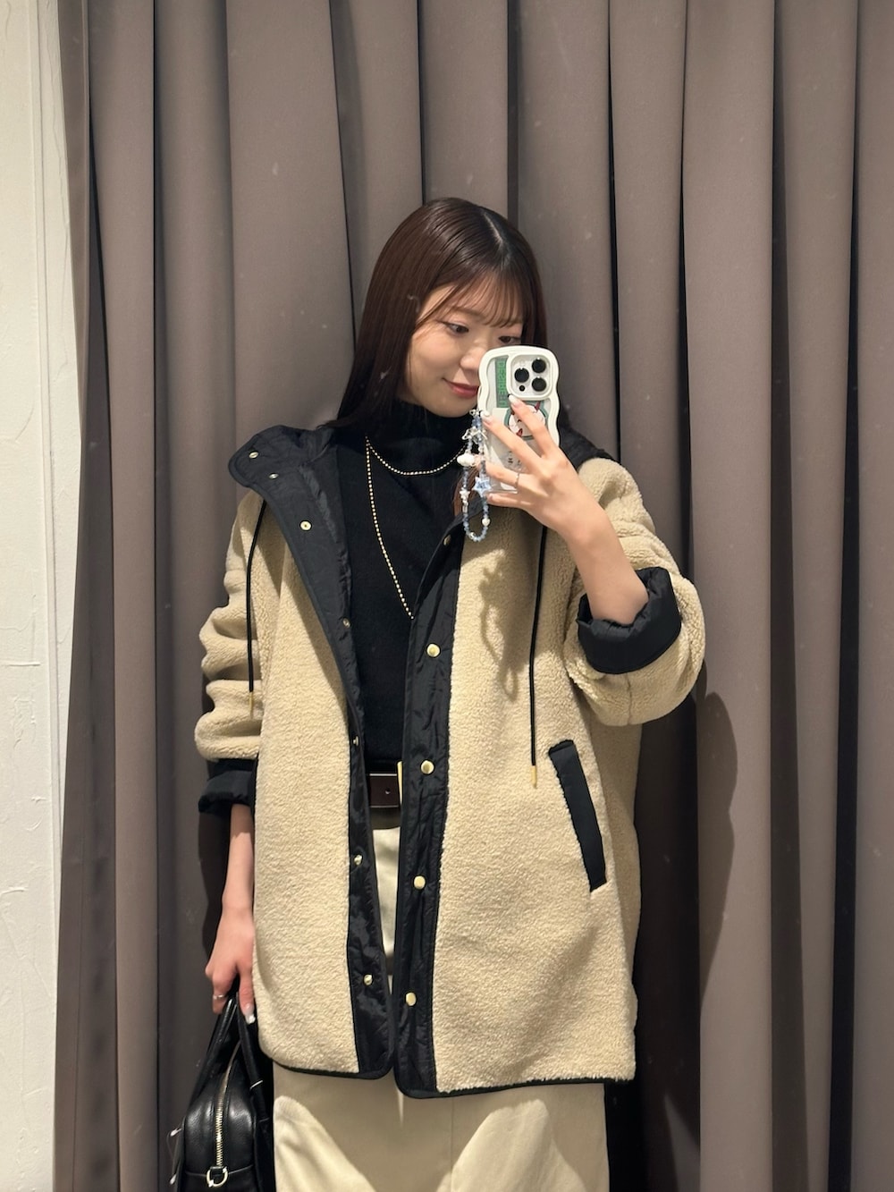 ベージュ系のその他アウター、ベージュ系のスカート、ブラック系のボストンバッグを着用したレディースの秋コーディネートの2枚目の写真