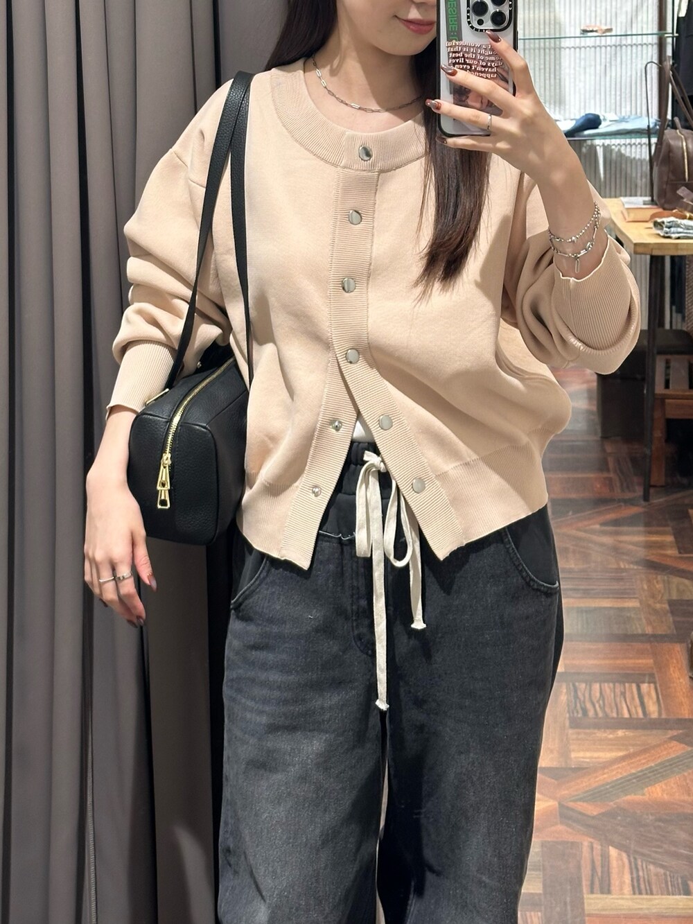 ブラック系のデニムパンツ、ピンク系のカーディガン/ボレロ、ブラック系のショルダーバッグを着用したレディースの秋コーディネートの2枚目の写真