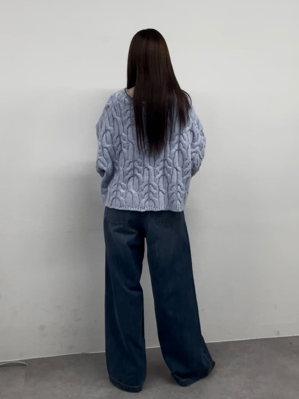 ブルー系のニット/セーター、ブルー系のデニムパンツ、ブラウン系のブーツを着用したレディースの秋コーディネートの3枚目の写真