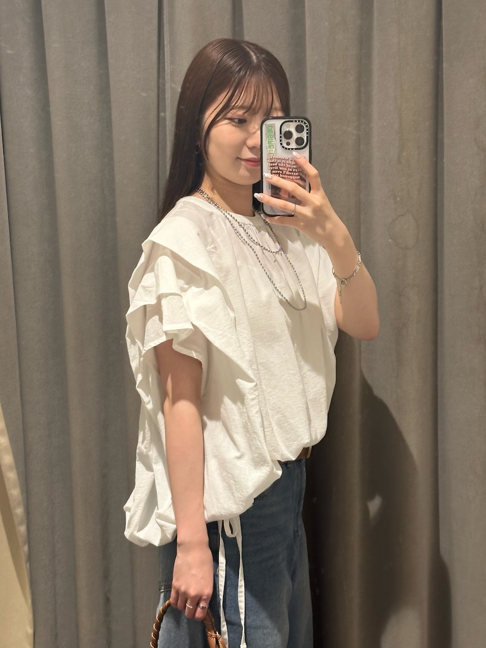 ブルー系のデニムパンツ、ホワイト系のシャツ/ブラウス、ブラウン系のハンドバッグを着用したレディースの夏コーディネートの4枚目の写真