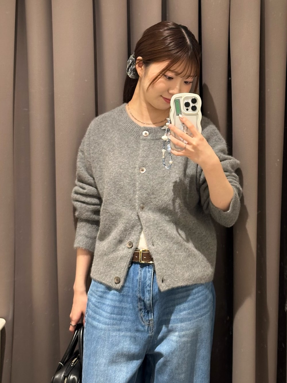 ブルー系のデニムパンツ、グレー系のカーディガン/ボレロ、ブラック系のボストンバッグを着用したレディースの秋コーディネートの2枚目の写真