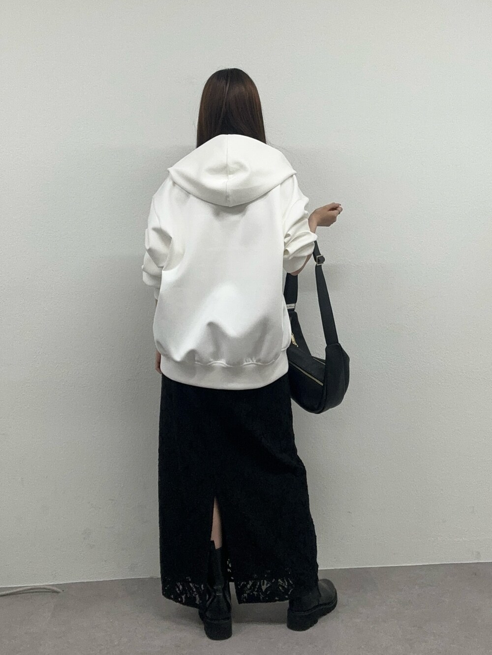 ホワイト系のパーカー、ブラック系のスカート、ブラック系のブーツを着用したレディースの冬コーディネートの3枚目の写真