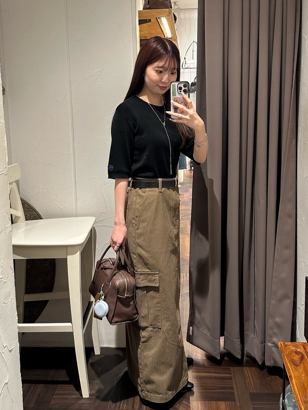 ブラウン系のスカート、ブラック系のニット/セーター、ブラウン系のボストンバッグを着用したレディースの秋コーディネートの5枚目の写真