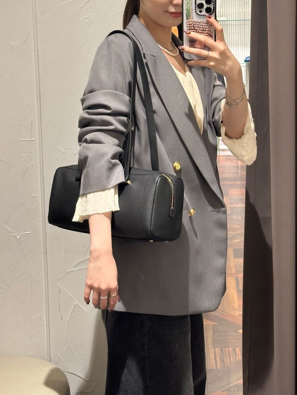 グレー系のテーラードジャケット、ブラック系のデニムパンツ、ブラック系のパンプスを着用したレディースの秋コーディネートの3枚目の写真