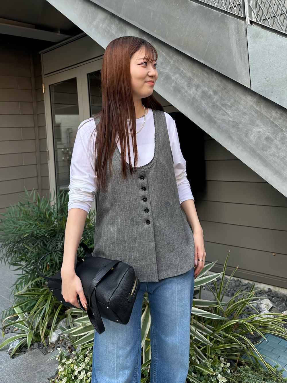 ブルー系のデニムパンツ、ホワイト系のTシャツ/カットソー、グレー系のベストを着用したレディースの秋コーディネートの3枚目の写真