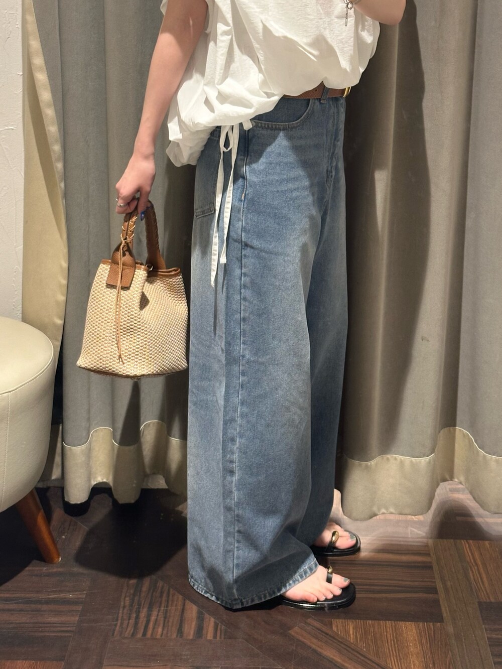 ブルー系のデニムパンツ、ホワイト系のシャツ/ブラウス、ブラウン系のハンドバッグを着用したレディースの夏コーディネートの6枚目の写真