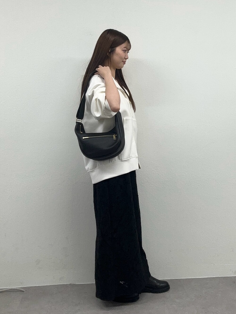 ホワイト系のパーカー、ブラック系のスカート、ブラック系のブーツを着用したレディースの冬コーディネートの2枚目の写真