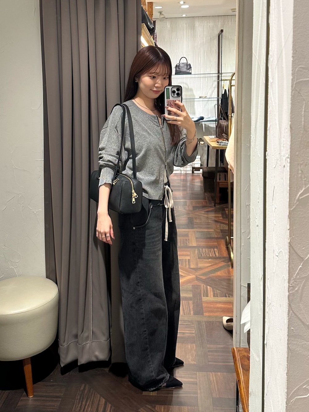 ブラック系のデニムパンツ、ブラック系のカーディガン/ボレロ、ブラック系のパンプスを着用したレディースの秋コーディネートの4枚目の写真