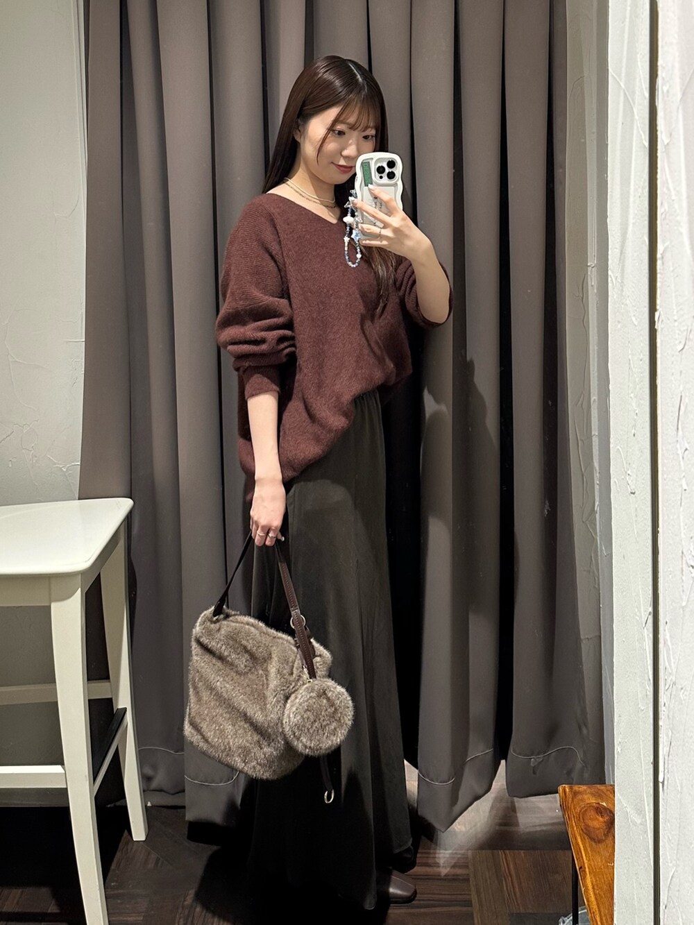 ブラウン系のスカート、レッド系のニット/セーター、ブラウン系のハンドバッグを着用したレディースの秋コーディネートの4枚目の写真