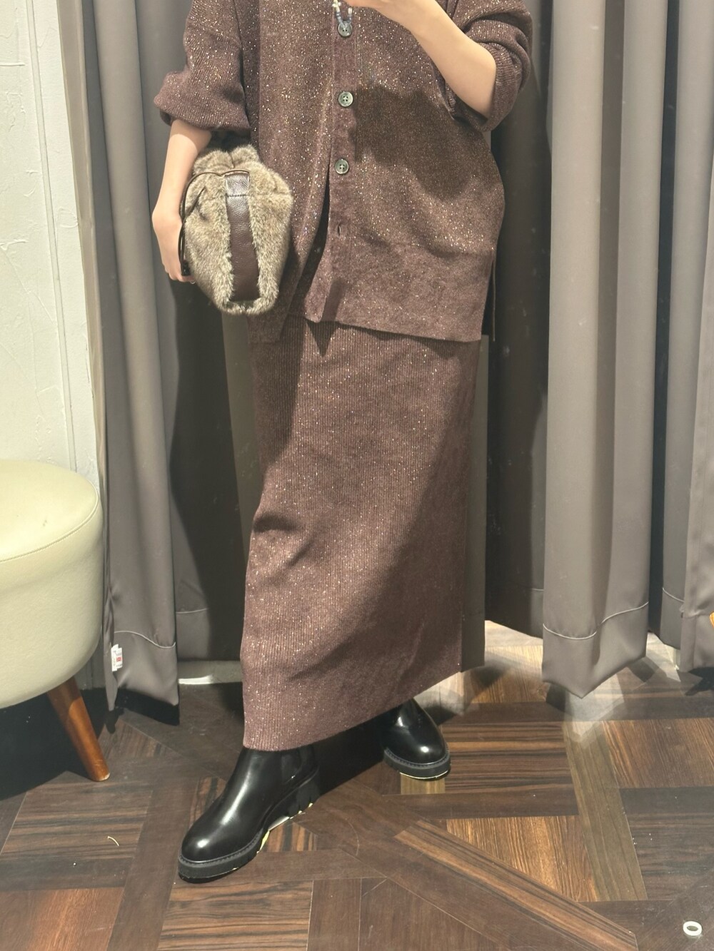 ブラウン系のニット/セーター、ブラウン系のスカート、ブラウン系のハンドバッグを着用したレディースの秋コーディネートの3枚目の写真