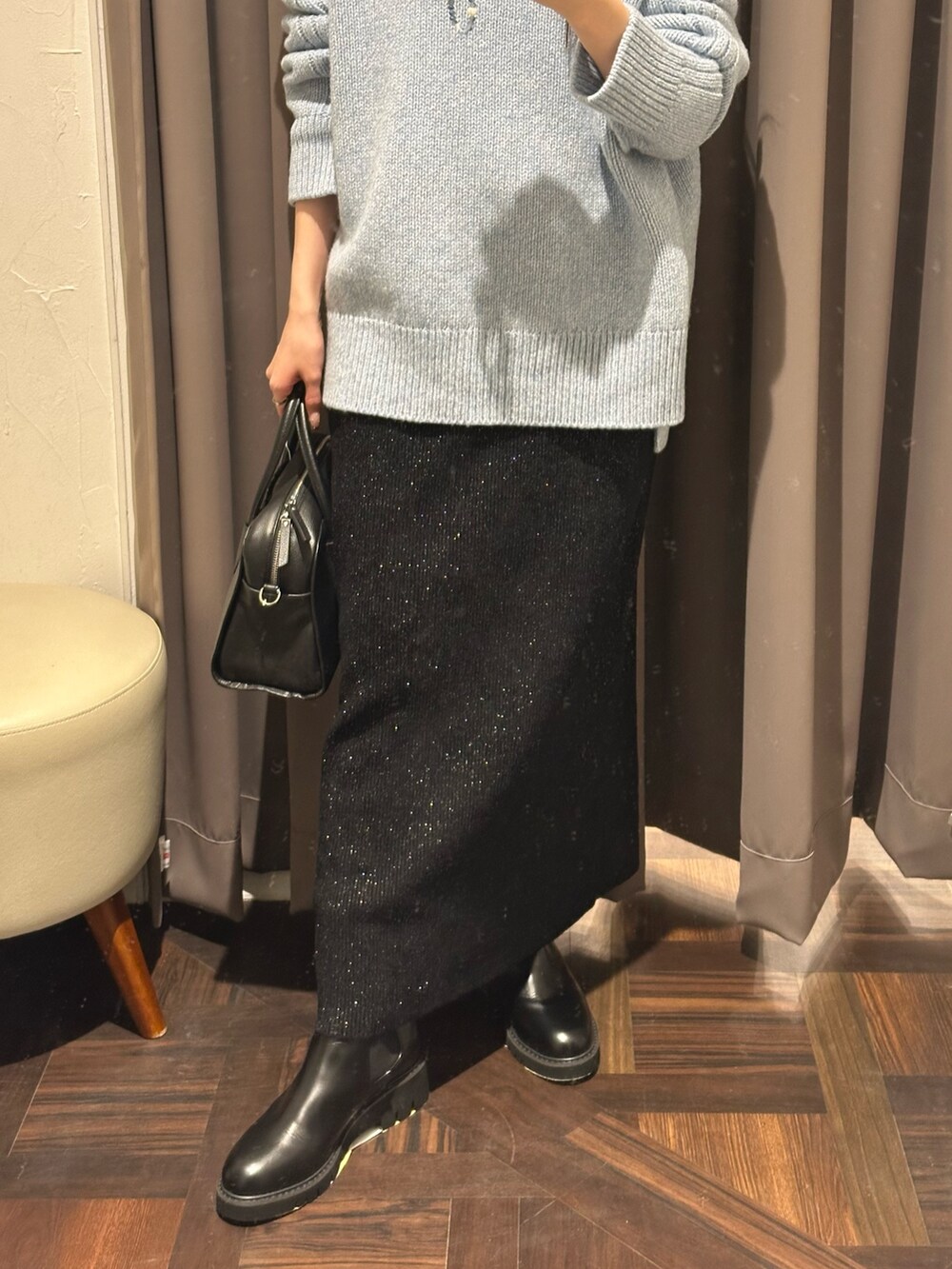 ブルー系のニット/セーター、ブラック系のスカート、ブラック系のブーツを着用したレディースの秋コーディネートの3枚目の写真