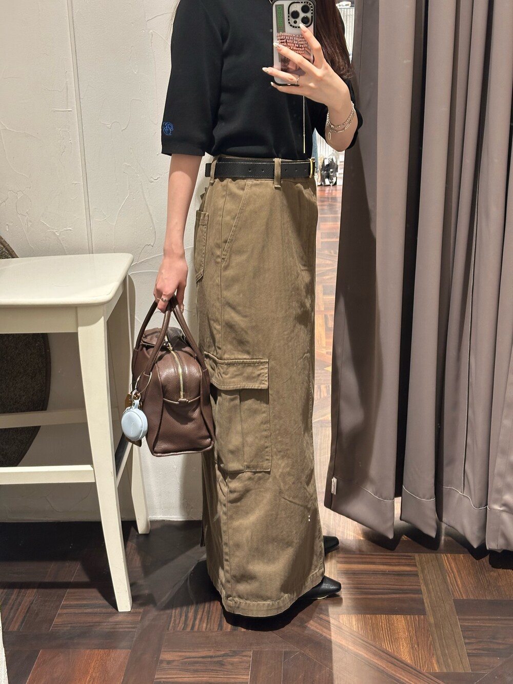 ブラウン系のスカート、ブラック系のニット/セーター、ブラウン系のボストンバッグを着用したレディースの秋コーディネートの4枚目の写真