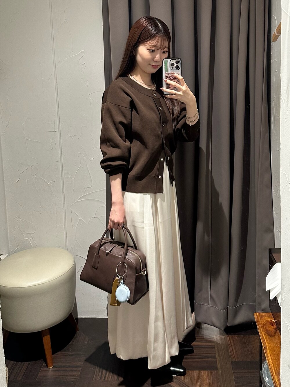 ホワイト系のスカート、ブラウン系のカーディガン/ボレロ、ブラウン系のボストンバッグを着用したレディースの秋コーディネートの4枚目の写真