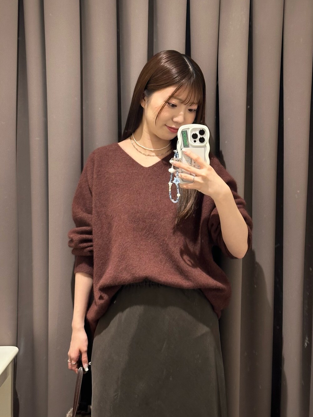 ブラウン系のスカート、レッド系のニット/セーター、ブラウン系のハンドバッグを着用したレディースの秋コーディネートの2枚目の写真