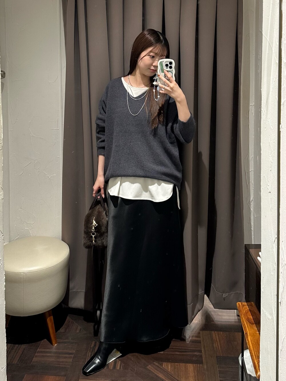 ブラック系のスカート、ホワイト系のTシャツ/カットソー、グレー系のニット/セーターを着用したレディースの冬コーディネートの4枚目の写真
