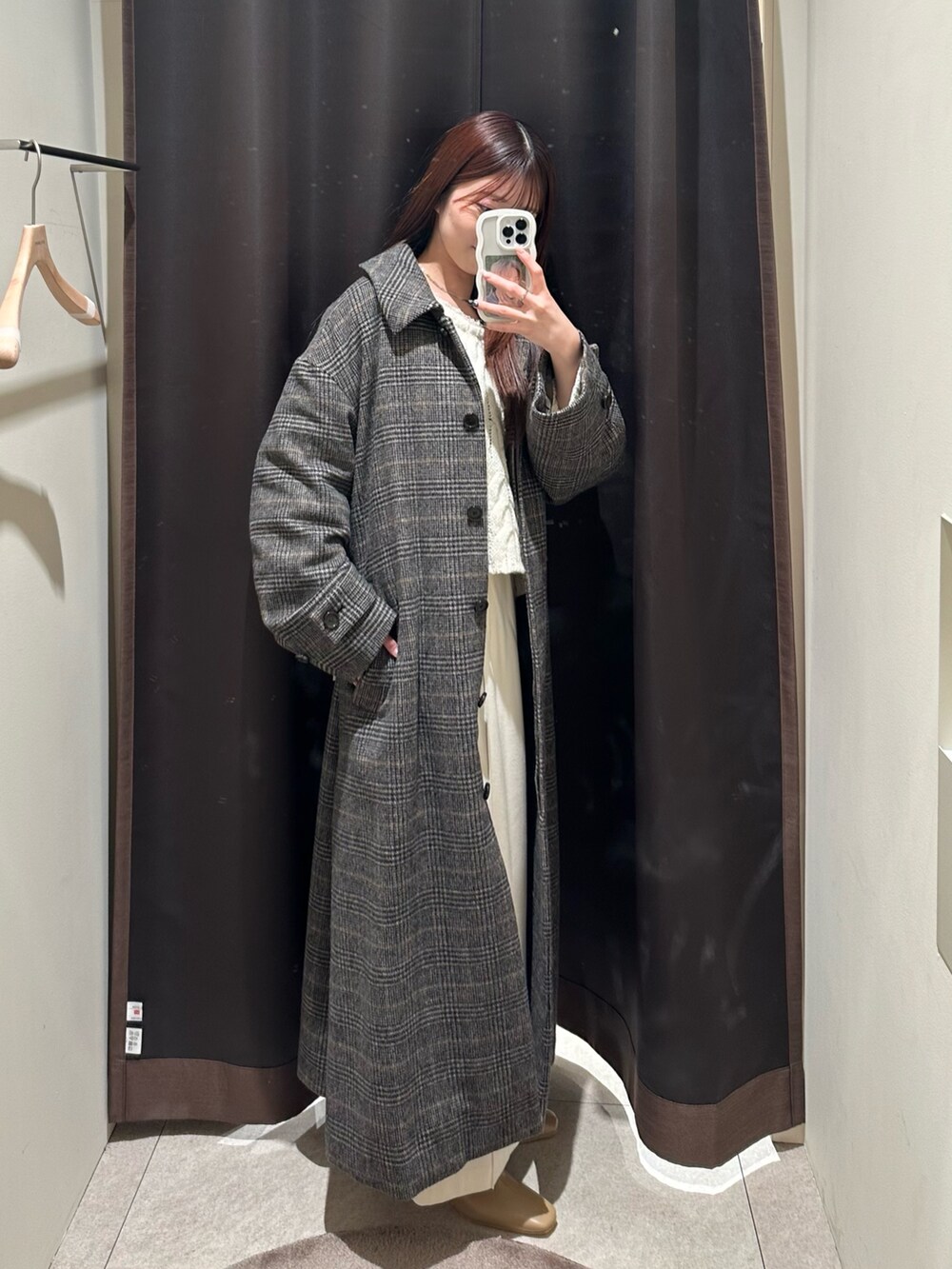 グレー系のステンカラーコート、ホワイト系のスカート、ホワイト系のニット/セーターを着用したレディースの冬コーディネートの2枚目の写真