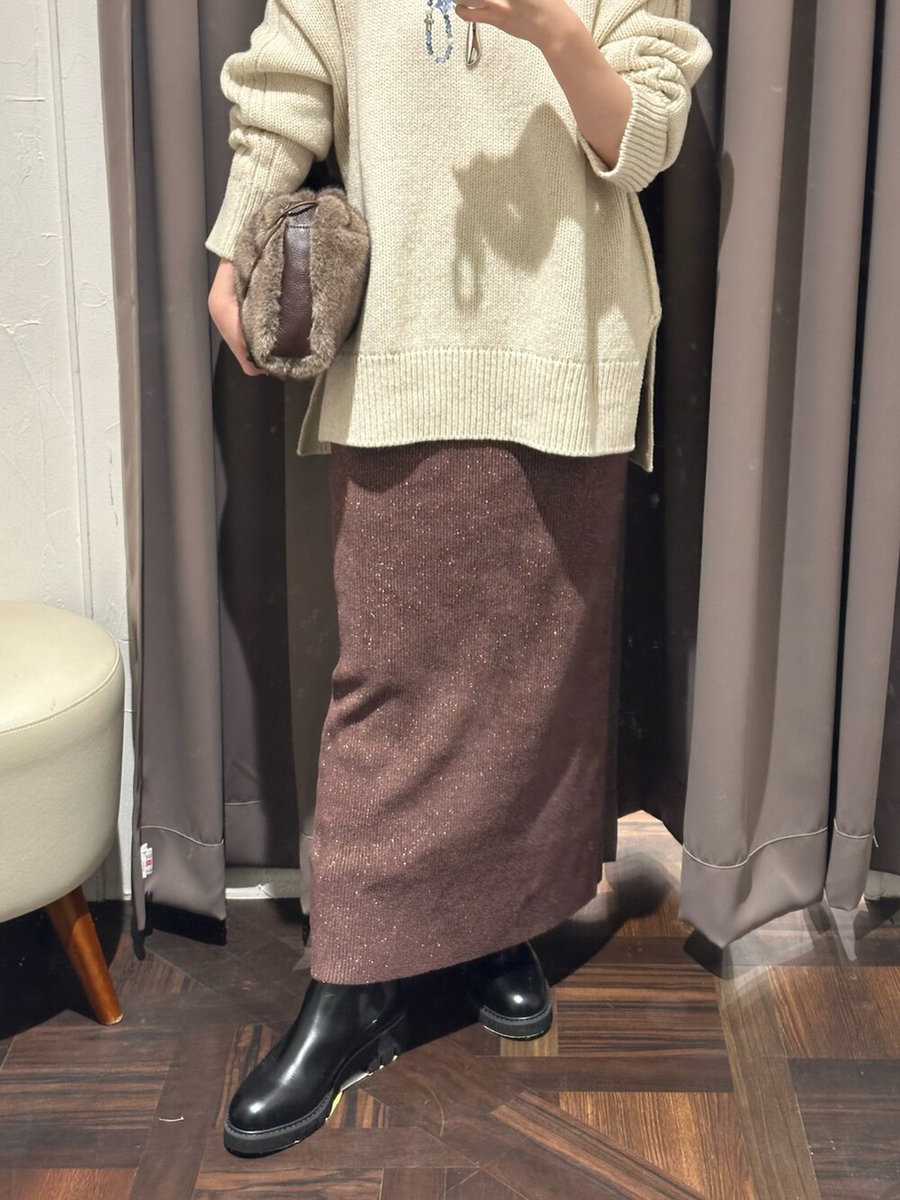 ブラウン系のスカート、ブラック系のブーツ、ブラウン系のハンドバッグを着用したレディースの秋コーディネートの3枚目の写真